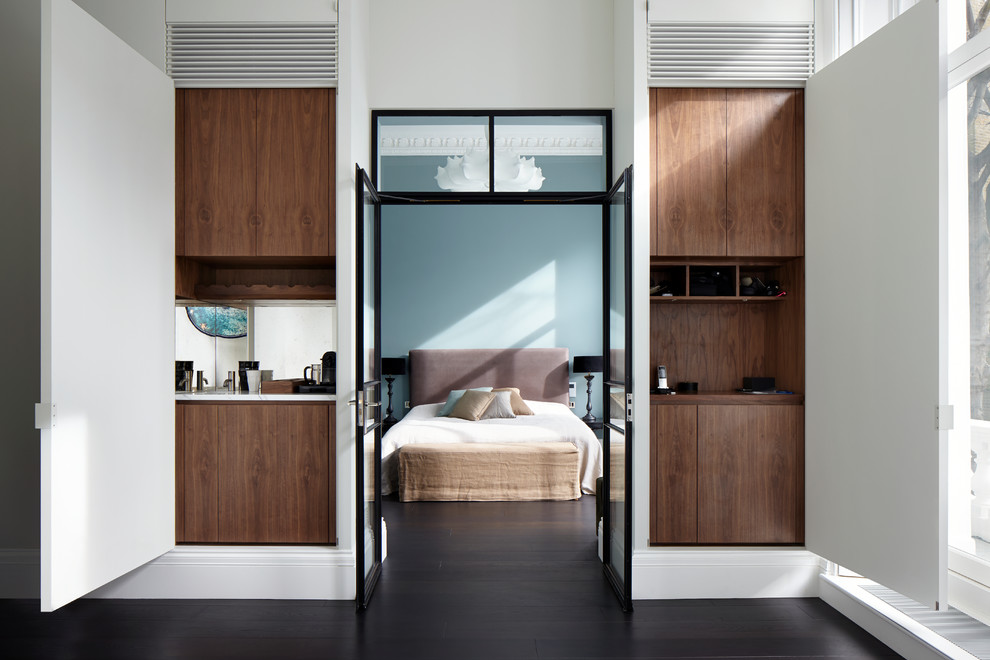 Large trendy master dark wood floor bedroom photo in London with blue walls