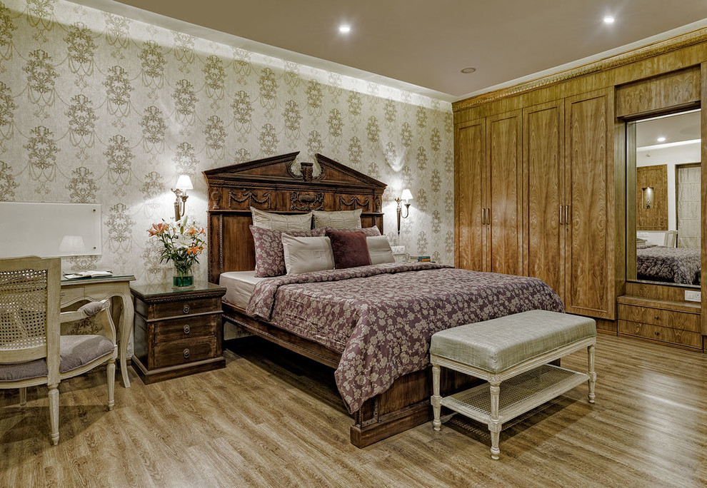 Medium sized traditional grey and brown bedroom in Pune with brown floors, beige walls, medium hardwood flooring and a feature wall.