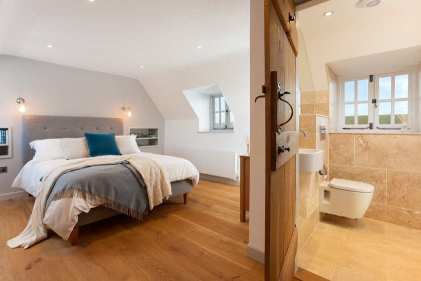 Large farmhouse master medium tone wood floor and brown floor bedroom photo in Kent with gray walls