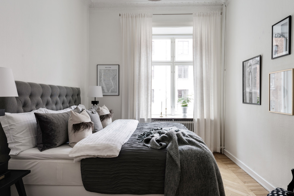 Design ideas for a scandinavian grey and black bedroom in Gothenburg with white walls, light hardwood flooring and beige floors.
