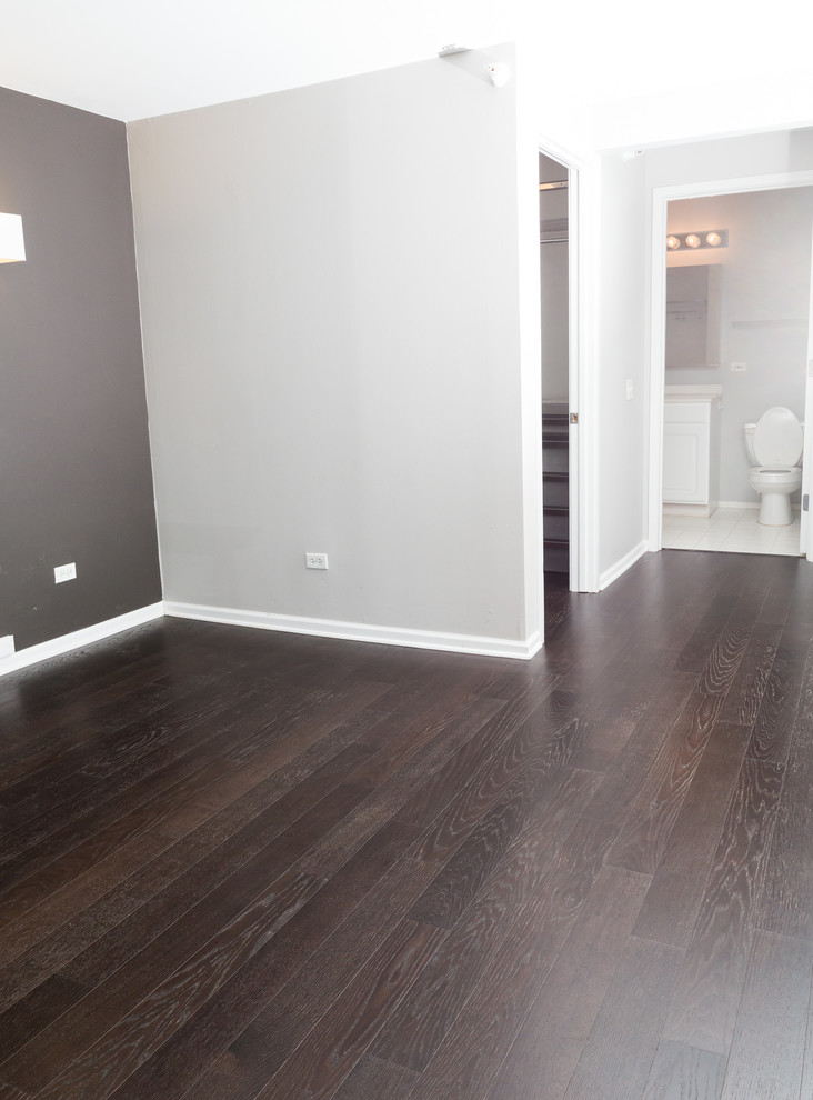 Foto de dormitorio principal minimalista pequeño sin chimenea con paredes grises, suelo de madera oscura y suelo marrón