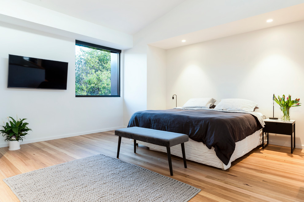 Réalisation d'une chambre design de taille moyenne avec un mur blanc et un sol en bois brun.