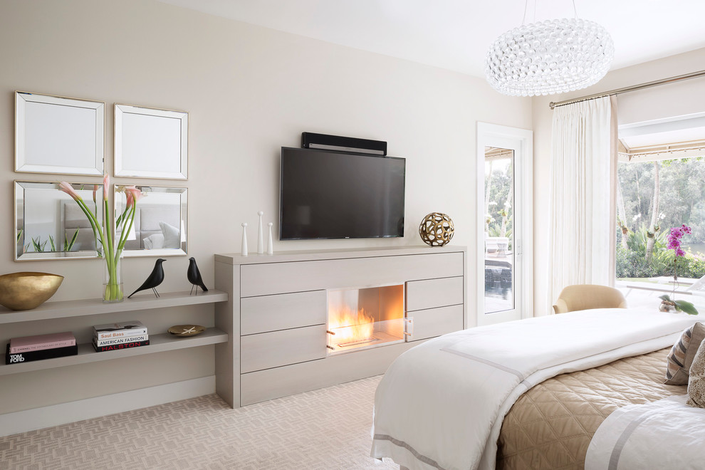 На фото: большая хозяйская спальня в стиле неоклассика (современная классика) с серыми стенами, ковровым покрытием, стандартным камином, фасадом камина из дерева и телевизором
