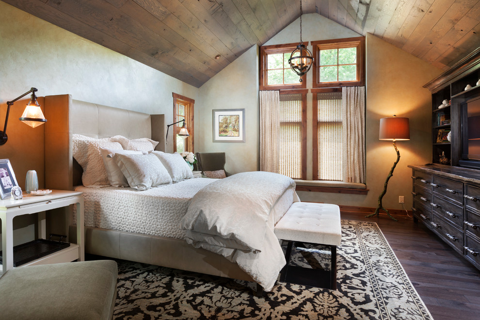 This is an example of a large rustic master bedroom in Milwaukee with dark hardwood flooring, beige walls, no fireplace and brown floors.