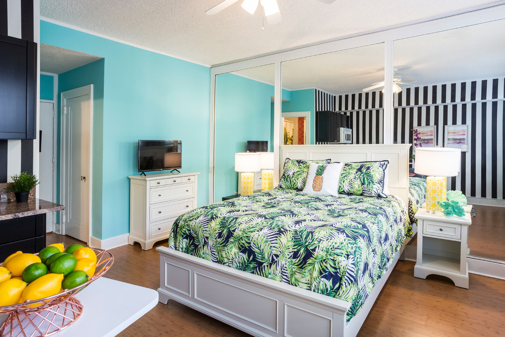 Foto di una camera da letto tropicale con pareti blu, pavimento in legno massello medio e pavimento marrone