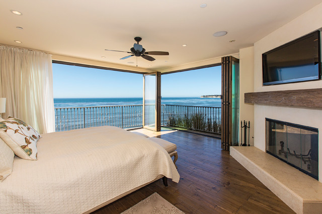 Large beach style master bedroom in Los Angeles with white walls, light hardwood flooring, a standard fireplace and a stone fireplace surround.