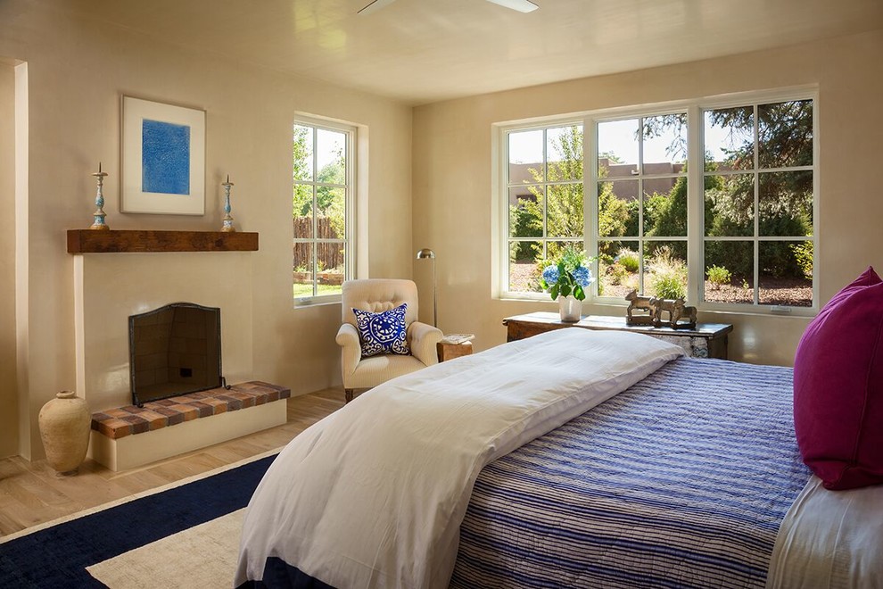 Foto de dormitorio principal de estilo americano de tamaño medio con paredes beige, suelo de madera clara, todas las chimeneas y marco de chimenea de yeso