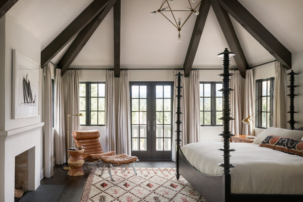 Mediterranes Hauptschlafzimmer mit weißer Wandfarbe, dunklem Holzboden, Kamin und braunem Boden in Portland