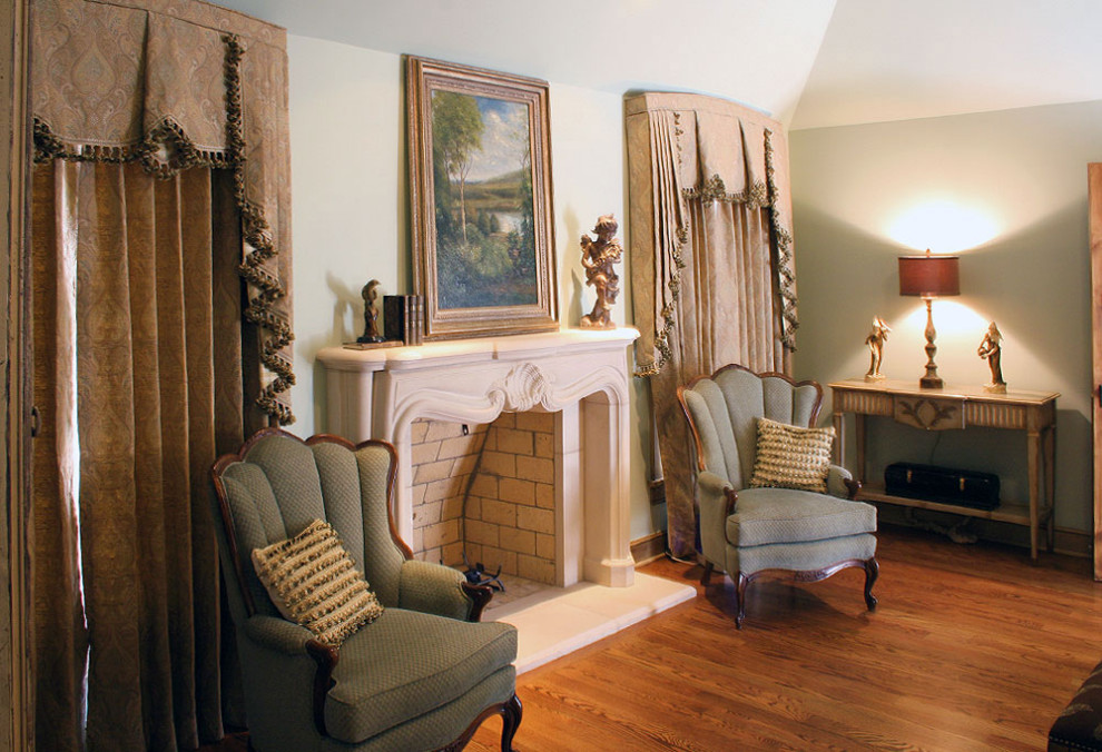 Geräumiges Hauptschlafzimmer mit grüner Wandfarbe, braunem Holzboden, Kamin und Kaminumrandung aus Stein
