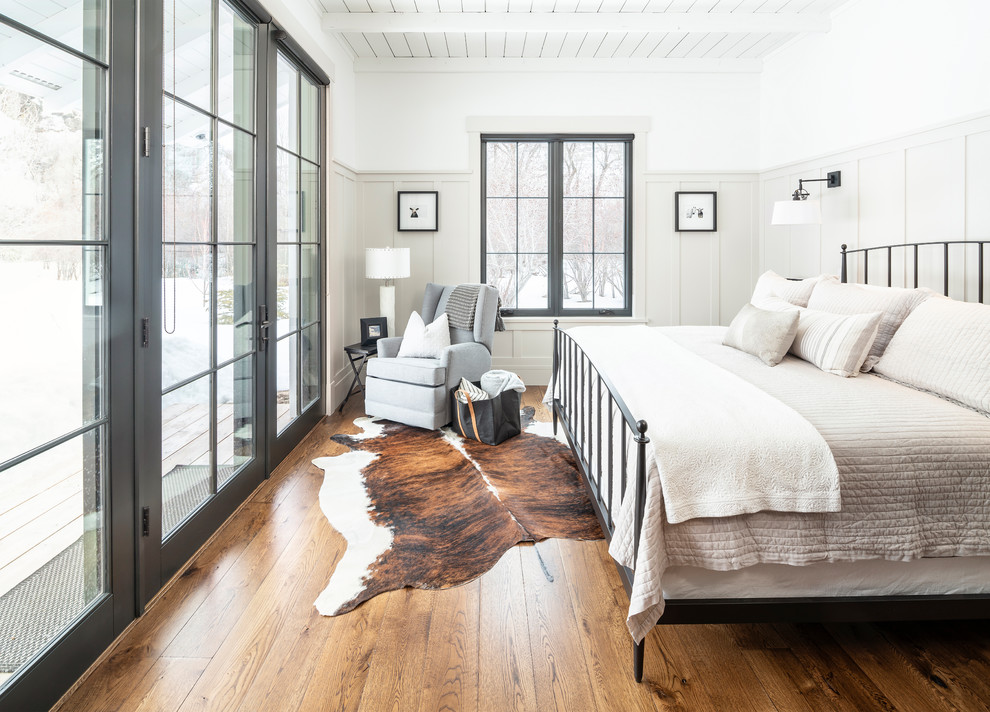 Lantlig inredning av ett sovrum, med vita väggar, mörkt trägolv och brunt golv