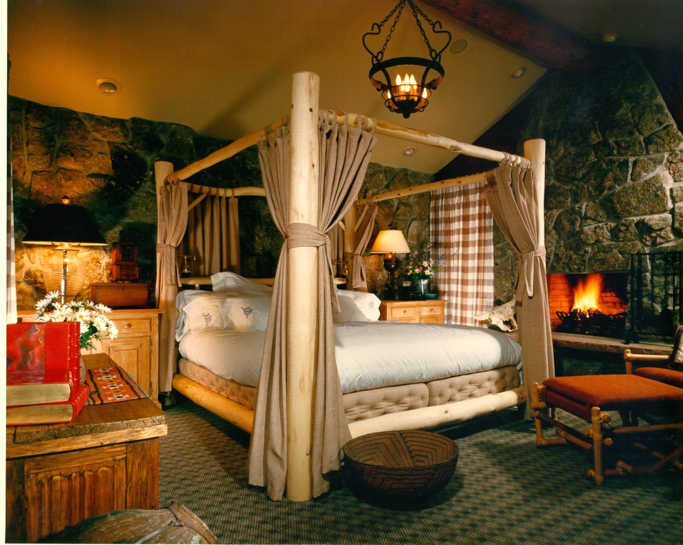 Foto de dormitorio principal rural grande con paredes beige, moqueta, todas las chimeneas y marco de chimenea de piedra