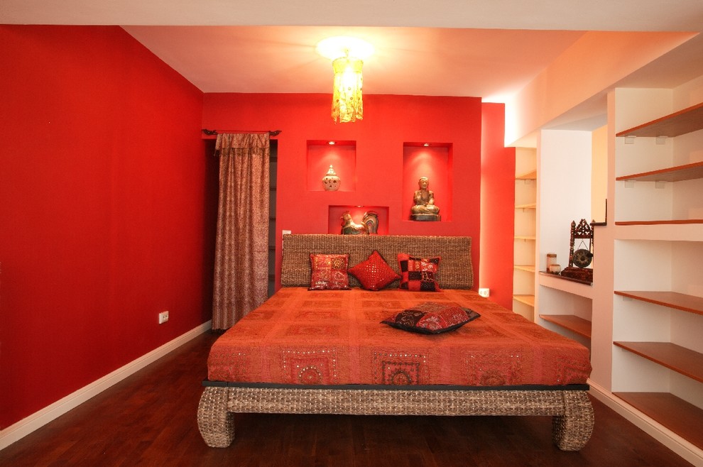 Cette photo montre une petite chambre parentale éclectique avec un mur rouge, parquet foncé et aucune cheminée.
