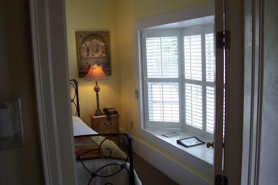 Ejemplo de habitación de invitados clásica de tamaño medio sin chimenea con paredes amarillas, suelo de madera en tonos medios y suelo marrón
