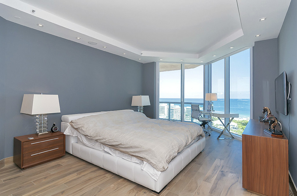 Photo of a large modern guest bedroom in Miami with grey walls, medium hardwood flooring and no fireplace.