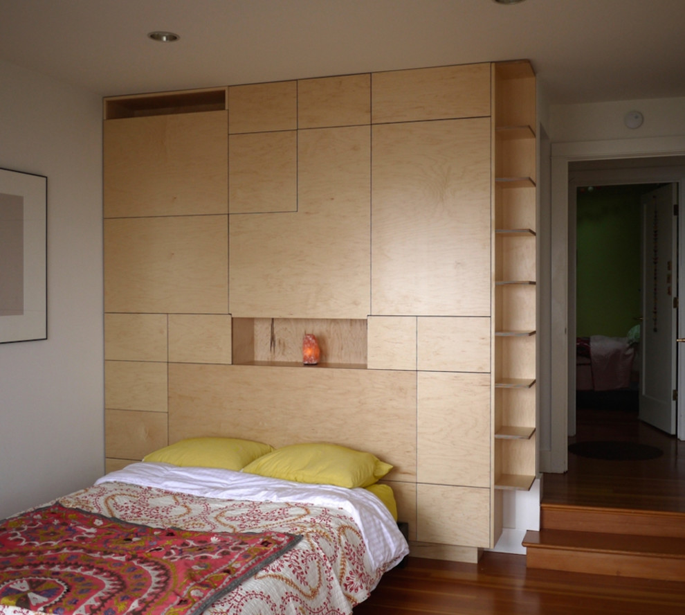 Esempio di una camera matrimoniale design di medie dimensioni con pareti bianche e pavimento in legno massello medio