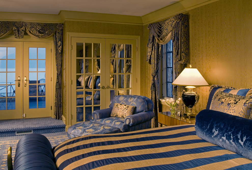 На фото: большая хозяйская спальня в классическом стиле с желтыми стенами, ковровым покрытием и синим полом без камина