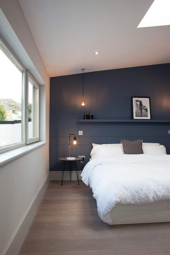 Cette image montre une chambre parentale design avec un mur bleu, parquet peint et un sol beige.