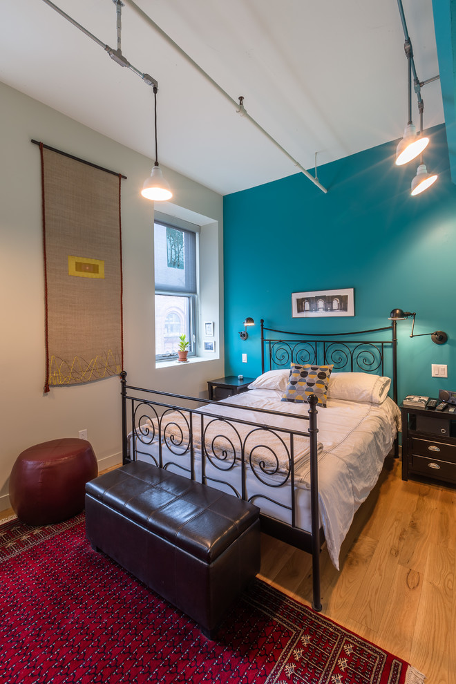 Esempio di una camera da letto industriale con pareti blu e parquet chiaro