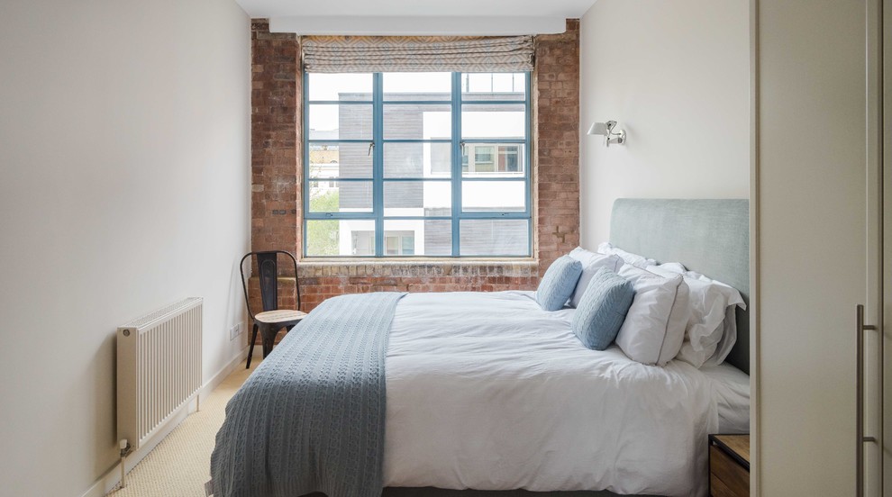 Imagen de dormitorio industrial con paredes blancas, moqueta y suelo beige