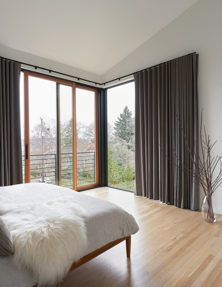 Example of a mid-sized danish master light wood floor and white floor bedroom design in Seattle with white walls and no fireplace