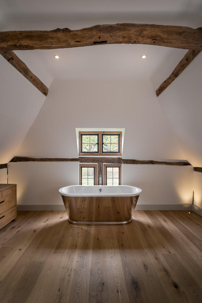 Modelo de habitación de invitados rural de tamaño medio sin chimenea con paredes blancas y suelo de madera en tonos medios