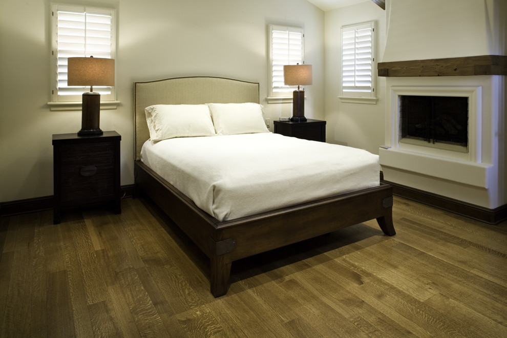Inspiration för medelhavsstil sovrum, med beige väggar, mellanmörkt trägolv och en standard öppen spis