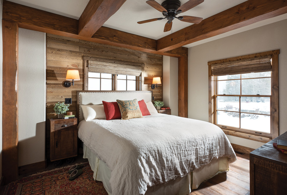Modelo de dormitorio principal rústico con paredes blancas, suelo de madera en tonos medios y suelo marrón