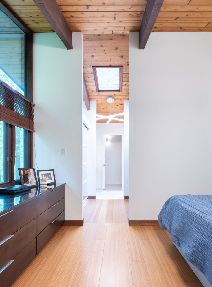 На фото: хозяйская спальня среднего размера в стиле ретро с белыми стенами, полом из бамбука и коричневым полом