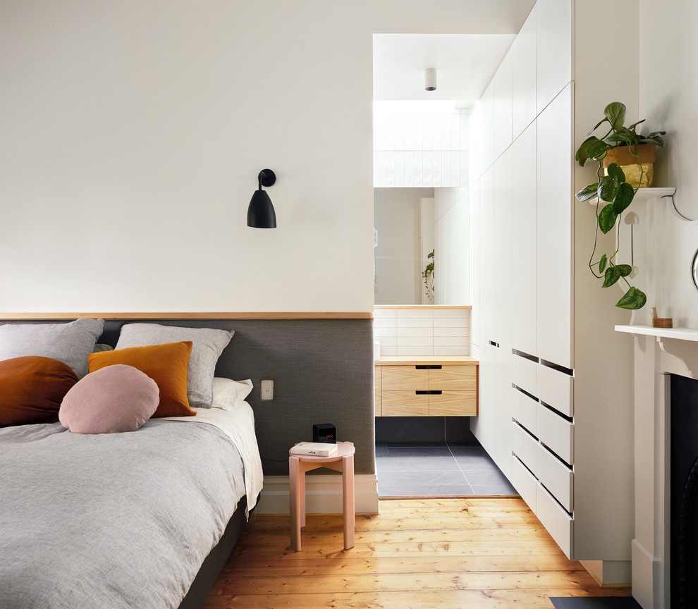 メルボルンにある小さなコンテンポラリースタイルのおしゃれな主寝室 (白い壁、標準型暖炉、茶色い床、無垢フローリング、グレーとブラウン) のインテリア