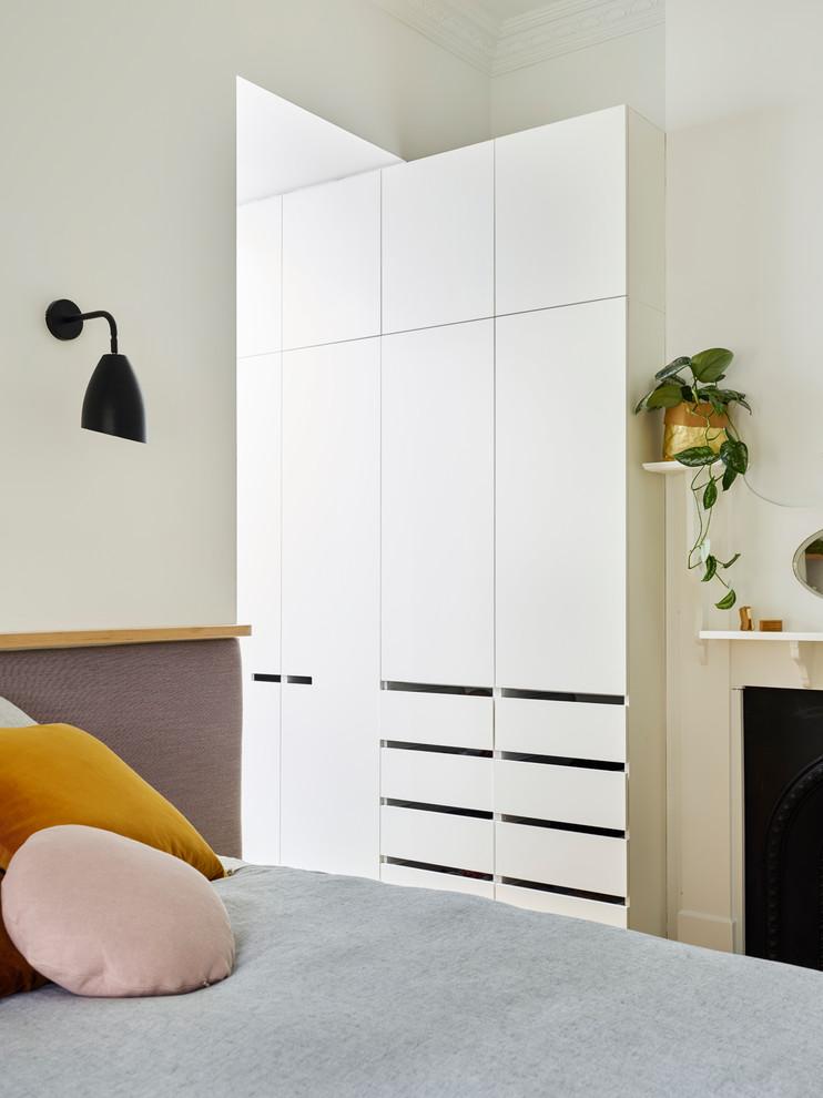 メルボルンにある小さなモダンスタイルのおしゃれな主寝室 (白い壁、淡色無垢フローリング、標準型暖炉、木材の暖炉まわり、茶色い床) のインテリア