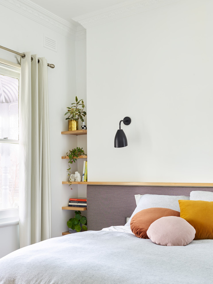 Пример оригинального дизайна: маленькая хозяйская спальня в стиле модернизм с белыми стенами, светлым паркетным полом, стандартным камином, фасадом камина из дерева и коричневым полом для на участке и в саду