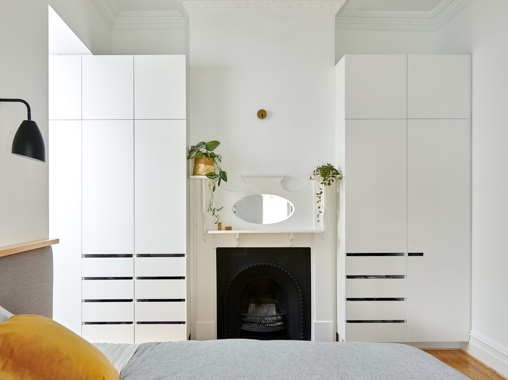 メルボルンにある小さなコンテンポラリースタイルのおしゃれな主寝室 (白い壁、標準型暖炉、木材の暖炉まわり、茶色い床、無垢フローリング、グレーとブラウン) のインテリア