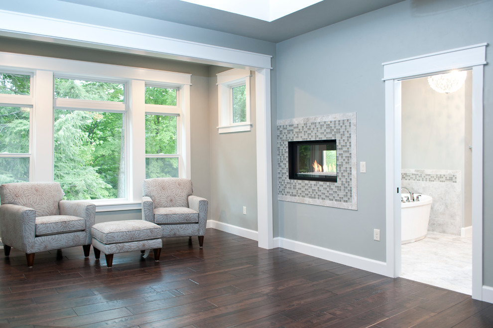 Photo of a large traditional master bedroom in Milwaukee with blue walls, dark hardwood flooring, a two-sided fireplace and a tiled fireplace surround.