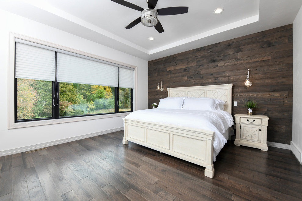 Modelo de dormitorio principal extra grande con paredes marrones, suelo de madera clara y suelo marrón