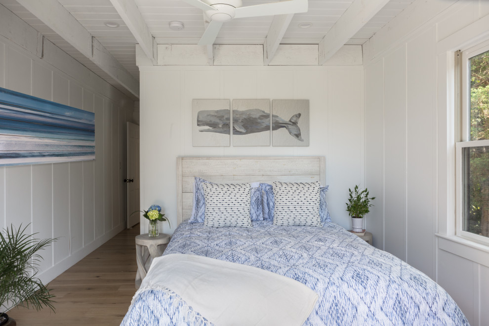 На фото: спальня в морском стиле с белыми стенами, светлым паркетным полом, бежевым полом, балками на потолке, потолком из вагонки и панелями на части стены с