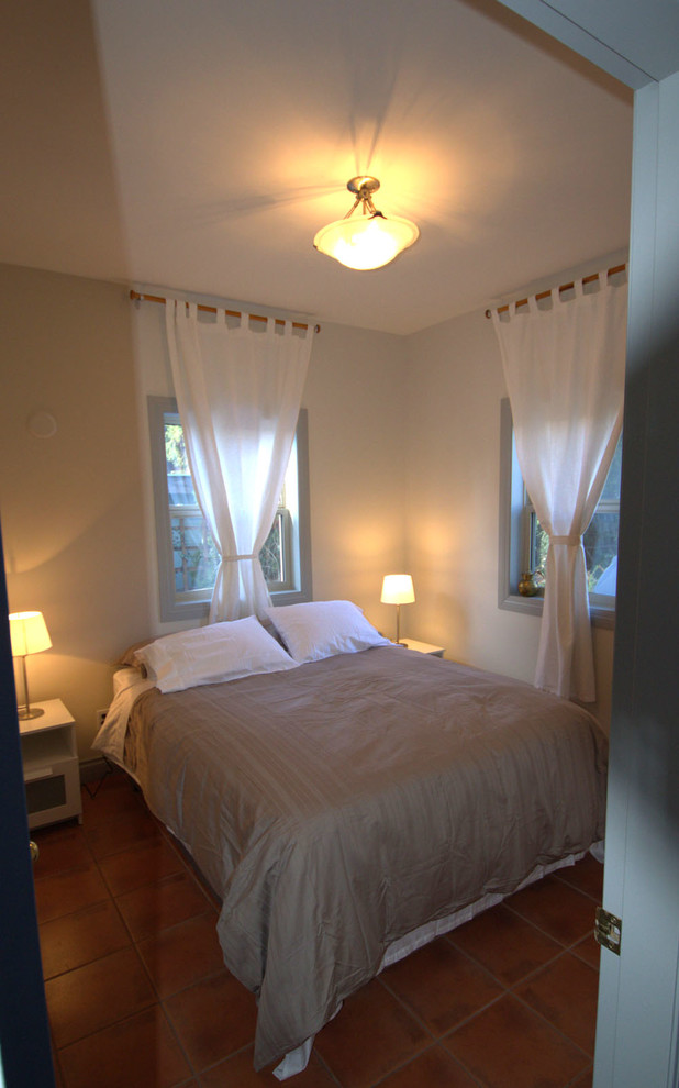 Ejemplo de habitación de invitados bohemia pequeña con paredes blancas y suelo de baldosas de terracota