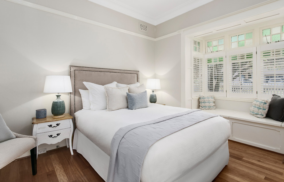 Modelo de dormitorio principal tradicional renovado de tamaño medio con paredes beige y suelo de madera en tonos medios