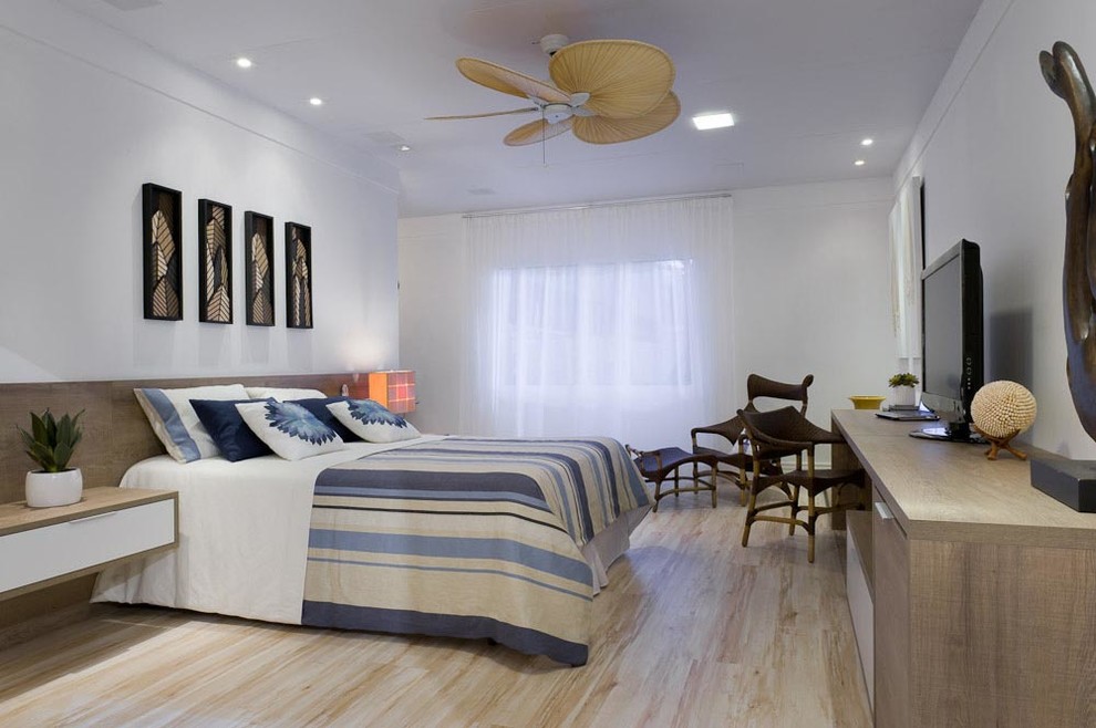 Ejemplo de dormitorio principal exótico grande sin chimenea con paredes blancas y suelo de madera clara