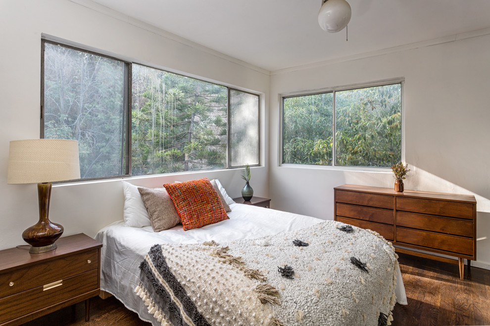 Mid-Century Schlafzimmer mit weißer Wandfarbe, dunklem Holzboden und braunem Boden in Los Angeles
