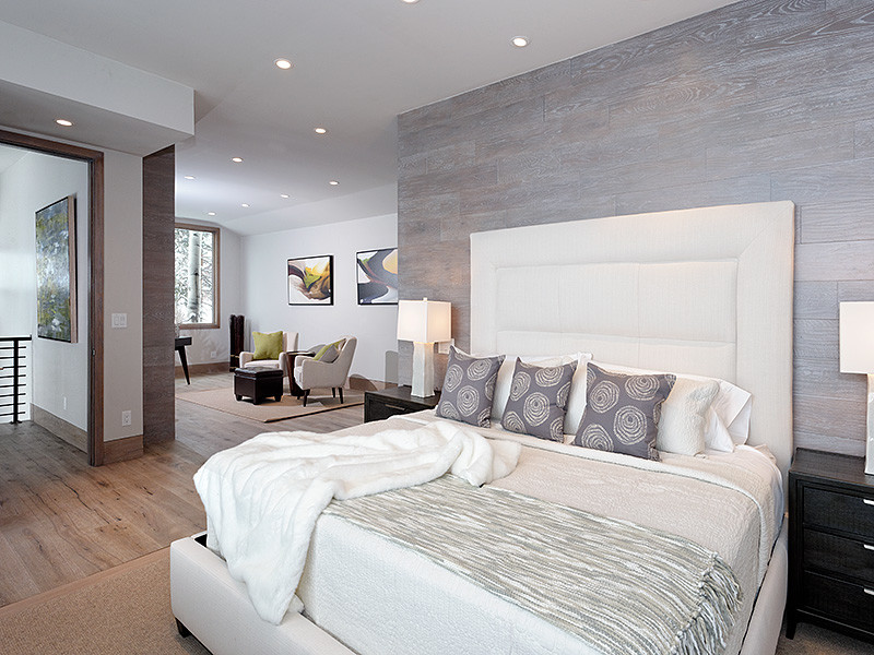 На фото: большая хозяйская спальня в современном стиле с серыми стенами, светлым паркетным полом, стандартным камином, фасадом камина из камня и коричневым полом
