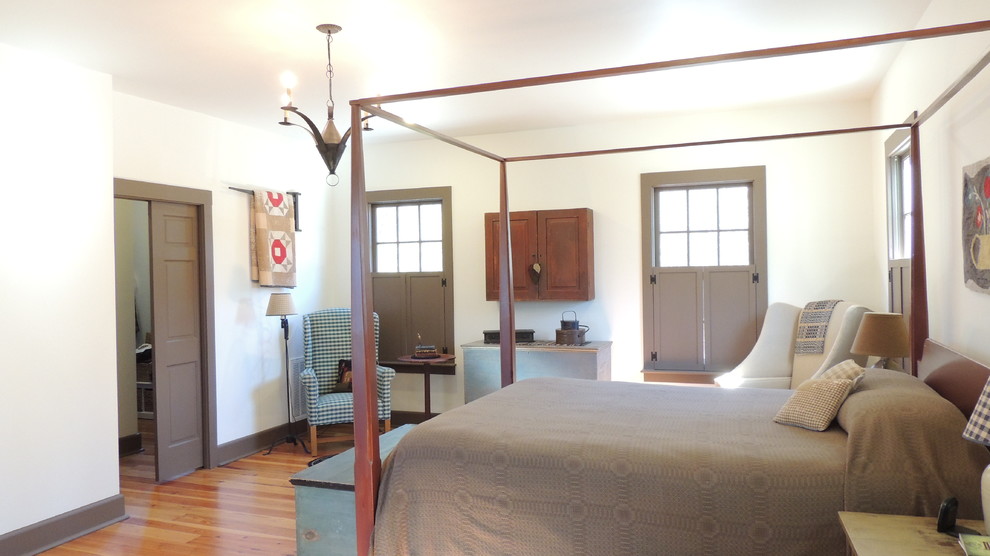 Imagen de dormitorio campestre con paredes blancas y suelo de madera en tonos medios