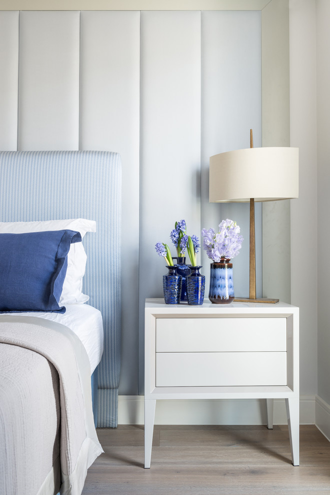 Trendy medium tone wood floor bedroom photo in London with blue walls