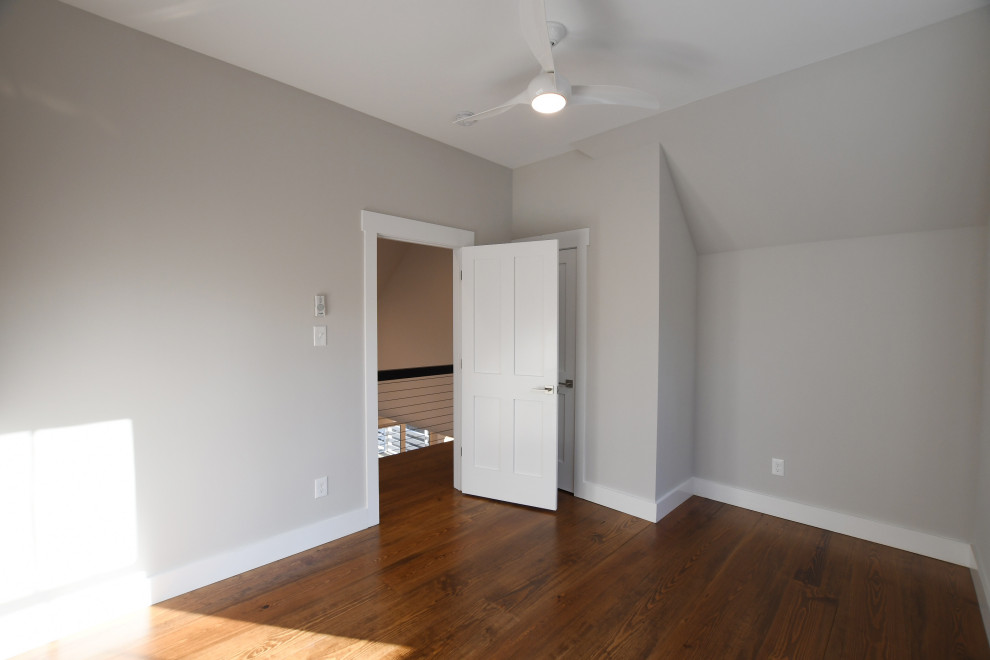 Immagine di una camera degli ospiti country di medie dimensioni con pareti grigie, pavimento in legno massello medio, pavimento marrone e soffitto a volta