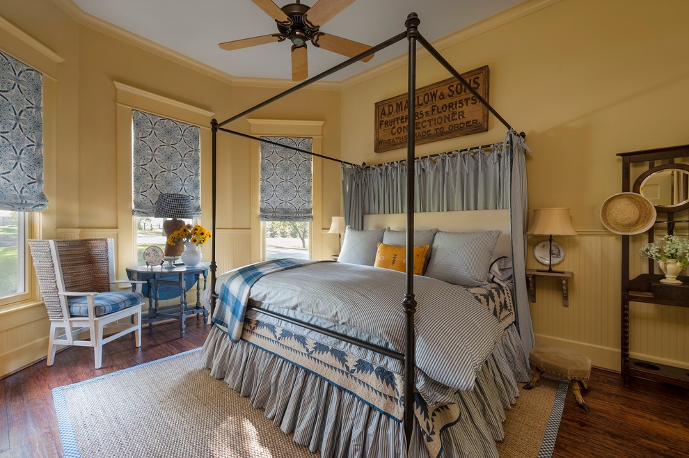 Modelo de dormitorio campestre con paredes amarillas y suelo de madera oscura