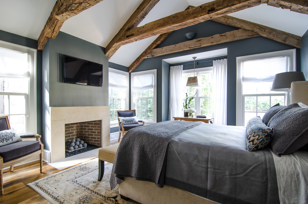 Idée de décoration pour une chambre champêtre avec une cheminée standard, un mur bleu et un sol en bois brun.