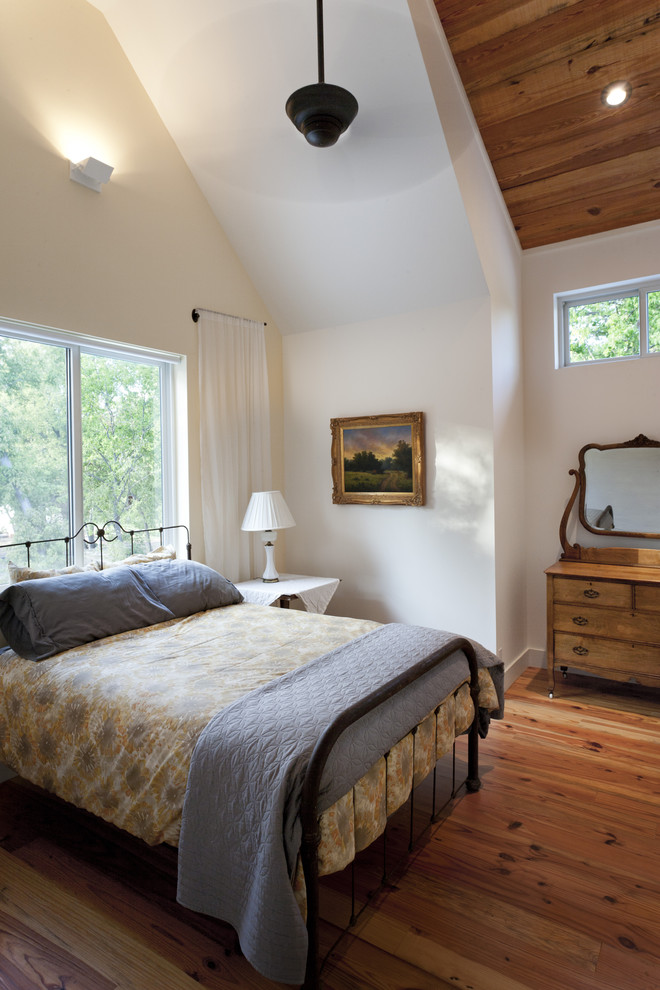 Example of a farmhouse medium tone wood floor bedroom design in Austin with white walls