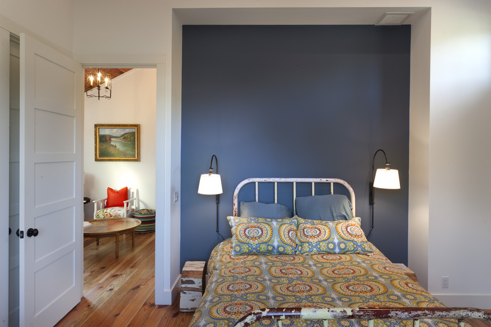 Réalisation d'une chambre d'amis champêtre avec un mur bleu, un sol en bois brun et aucune cheminée.