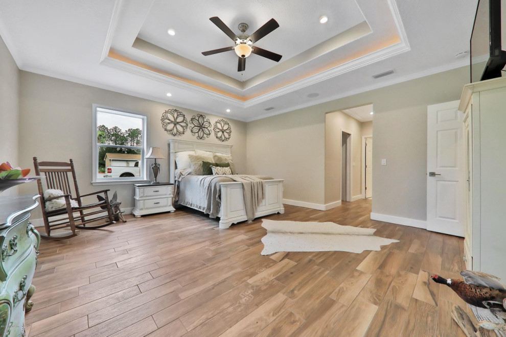 This is an example of a large rural master bedroom in Jacksonville with beige walls, no fireplace, brown floors and ceramic flooring.