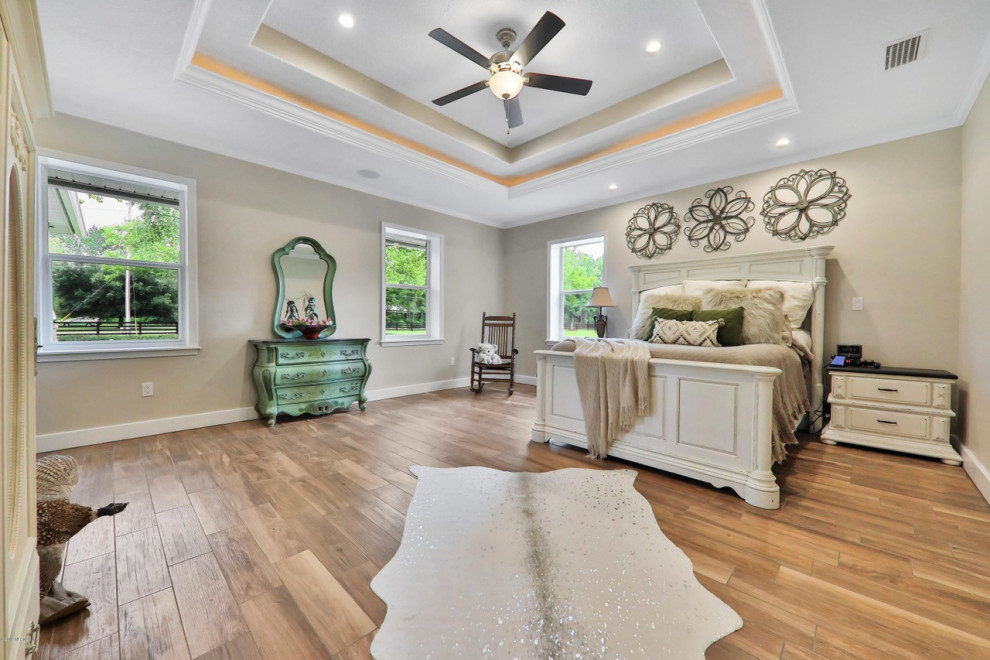 Großes Landhausstil Hauptschlafzimmer ohne Kamin mit beiger Wandfarbe, braunem Boden und Keramikboden in Jacksonville