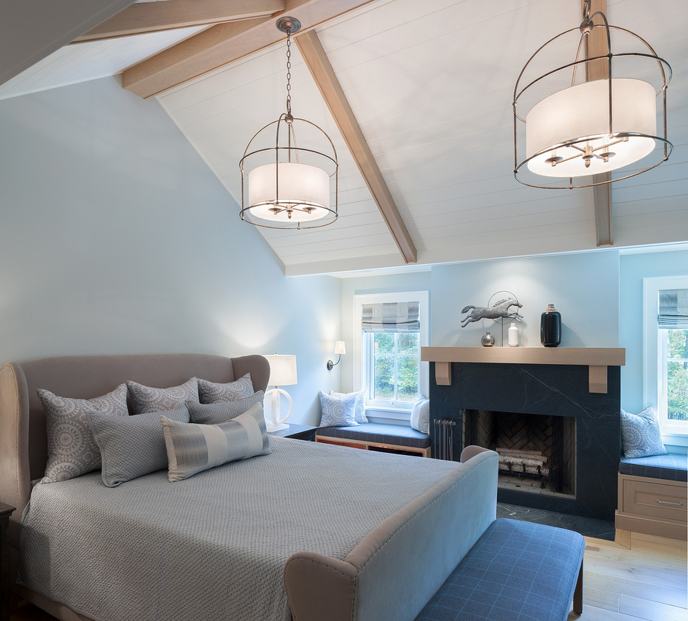 This is an example of a large country master bedroom in Grand Rapids with blue walls, light hardwood flooring, a standard fireplace, a stone fireplace surround and beige floors.
